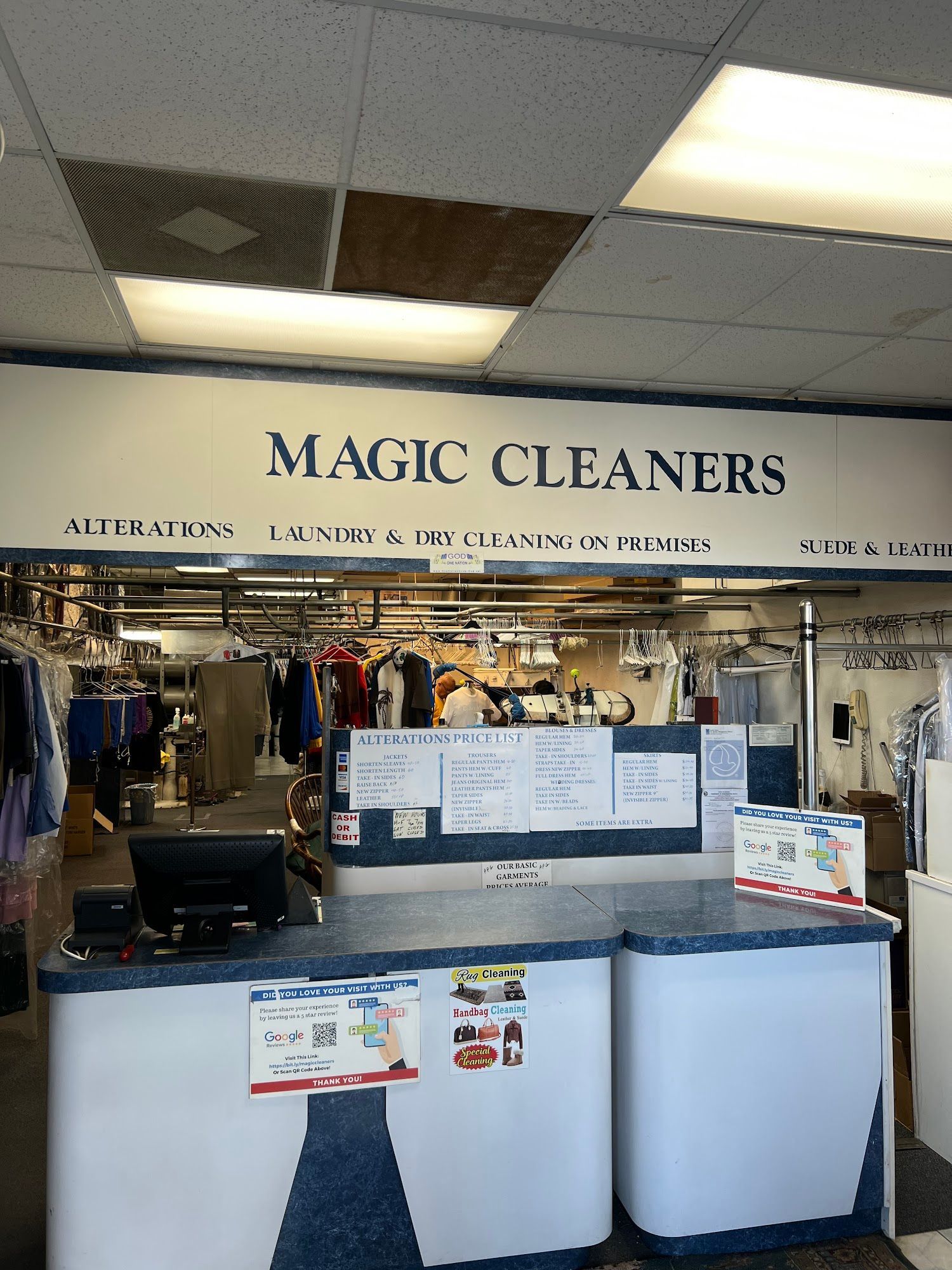 Interior of Magic Cleaners dry cleaner with a counter, clothing racks, and the business name above.