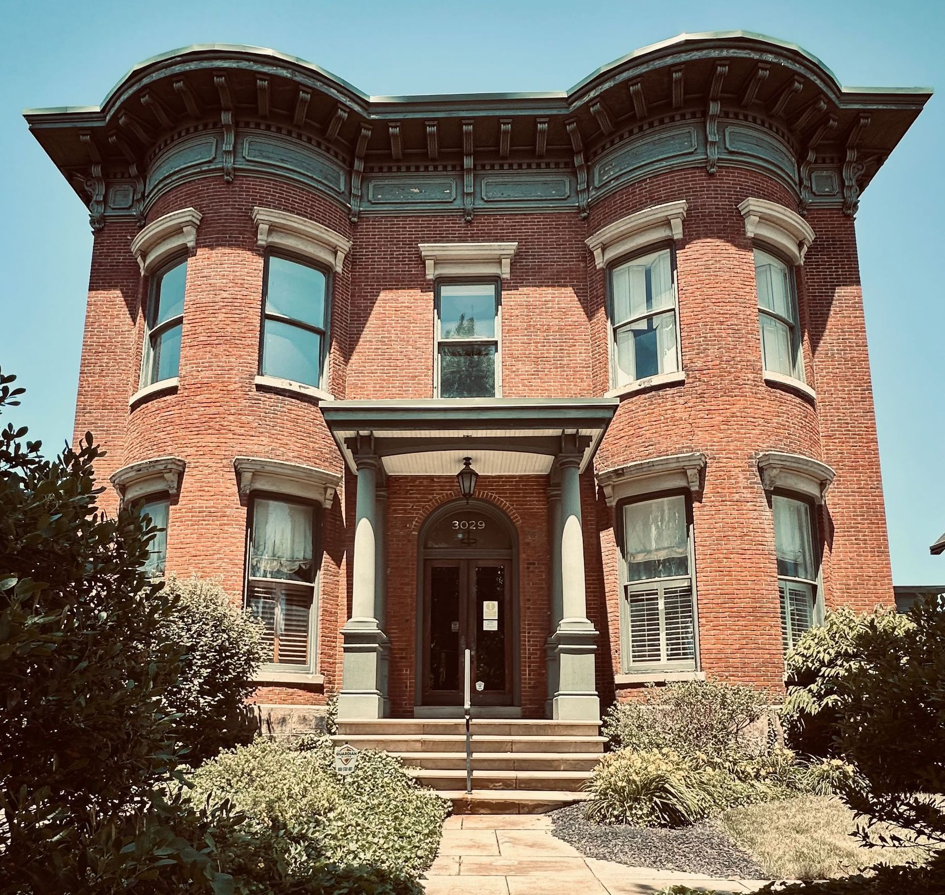 A large brick mansion with a blue sky in the background