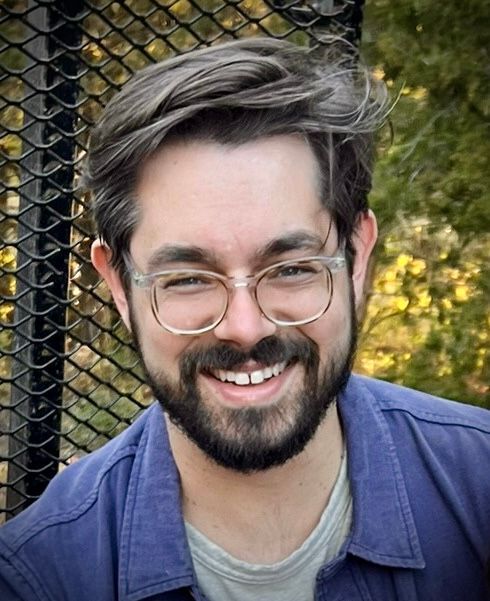A man with a beard and glasses is smiling for the camera.