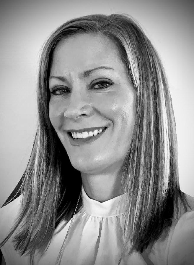 A woman with long hair is smiling in a black and white photo.