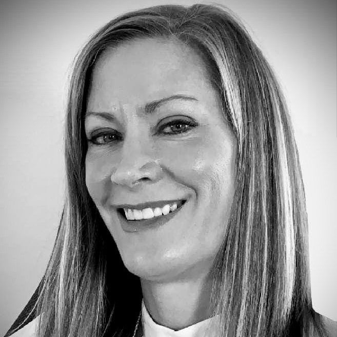 A woman with long hair is smiling in a black and white photo.