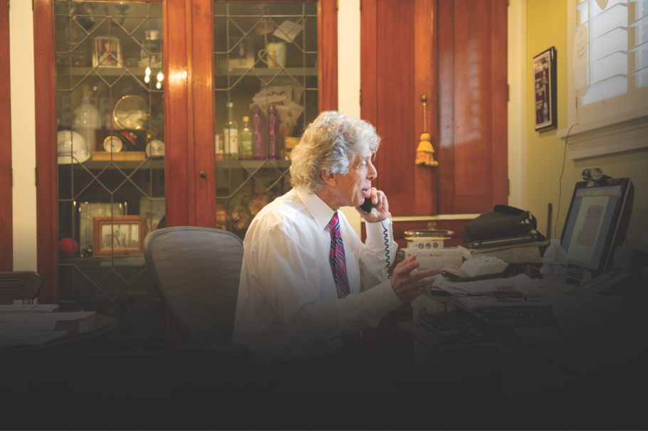 A man sitting at a desk talking on a cell phone