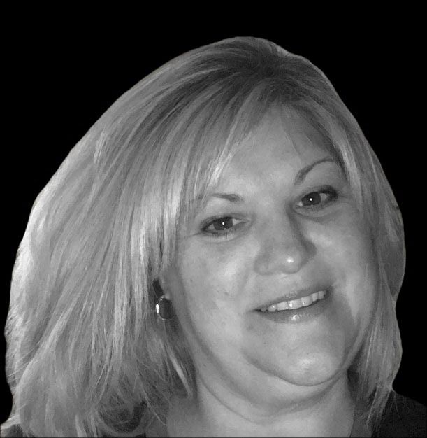 A woman with blonde hair is smiling in a black and white photo