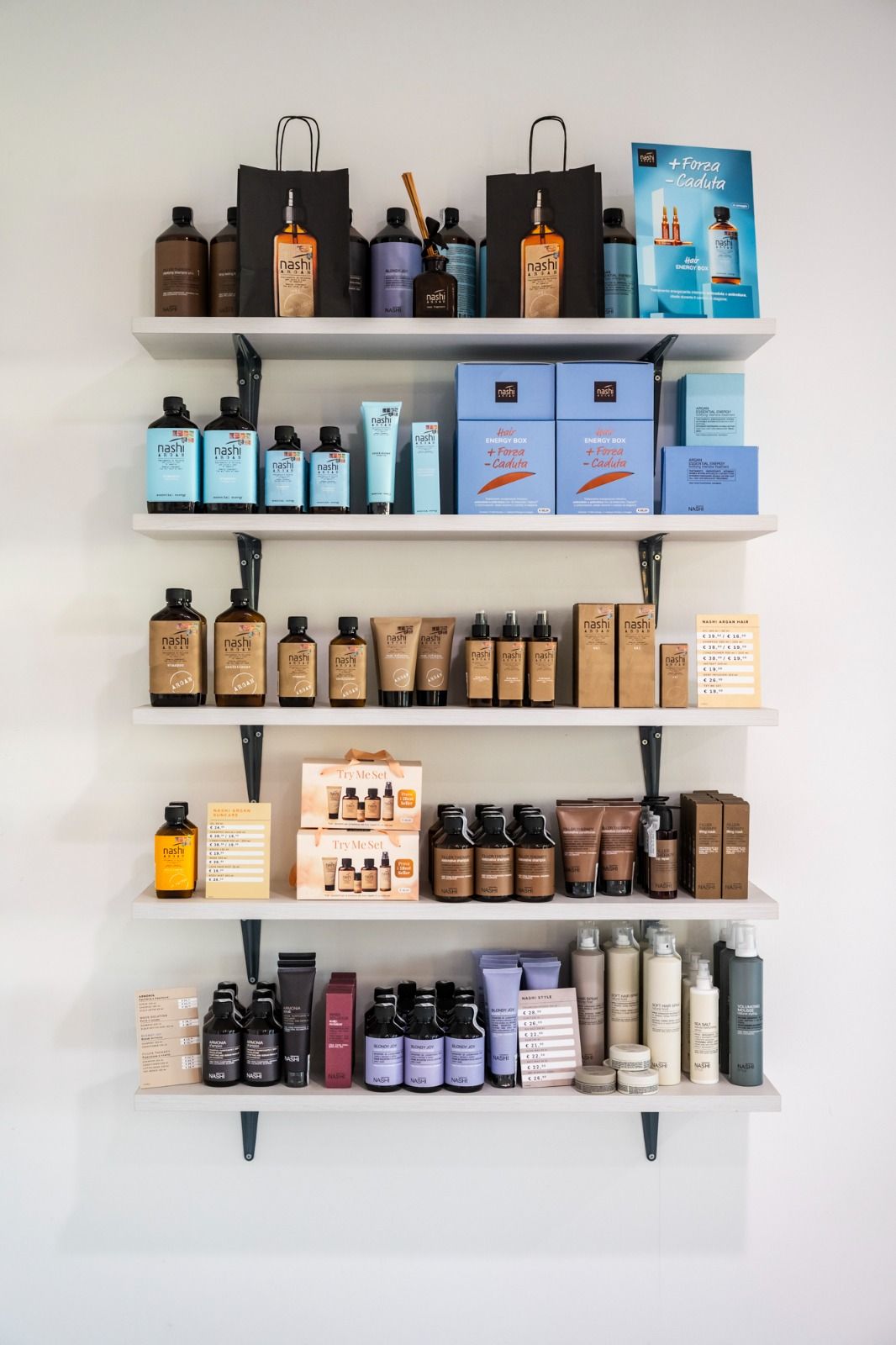 Scaffali che espongono vari prodotti cosmetici e per la cura della pelle in confezioni marroni, blu e bianche.