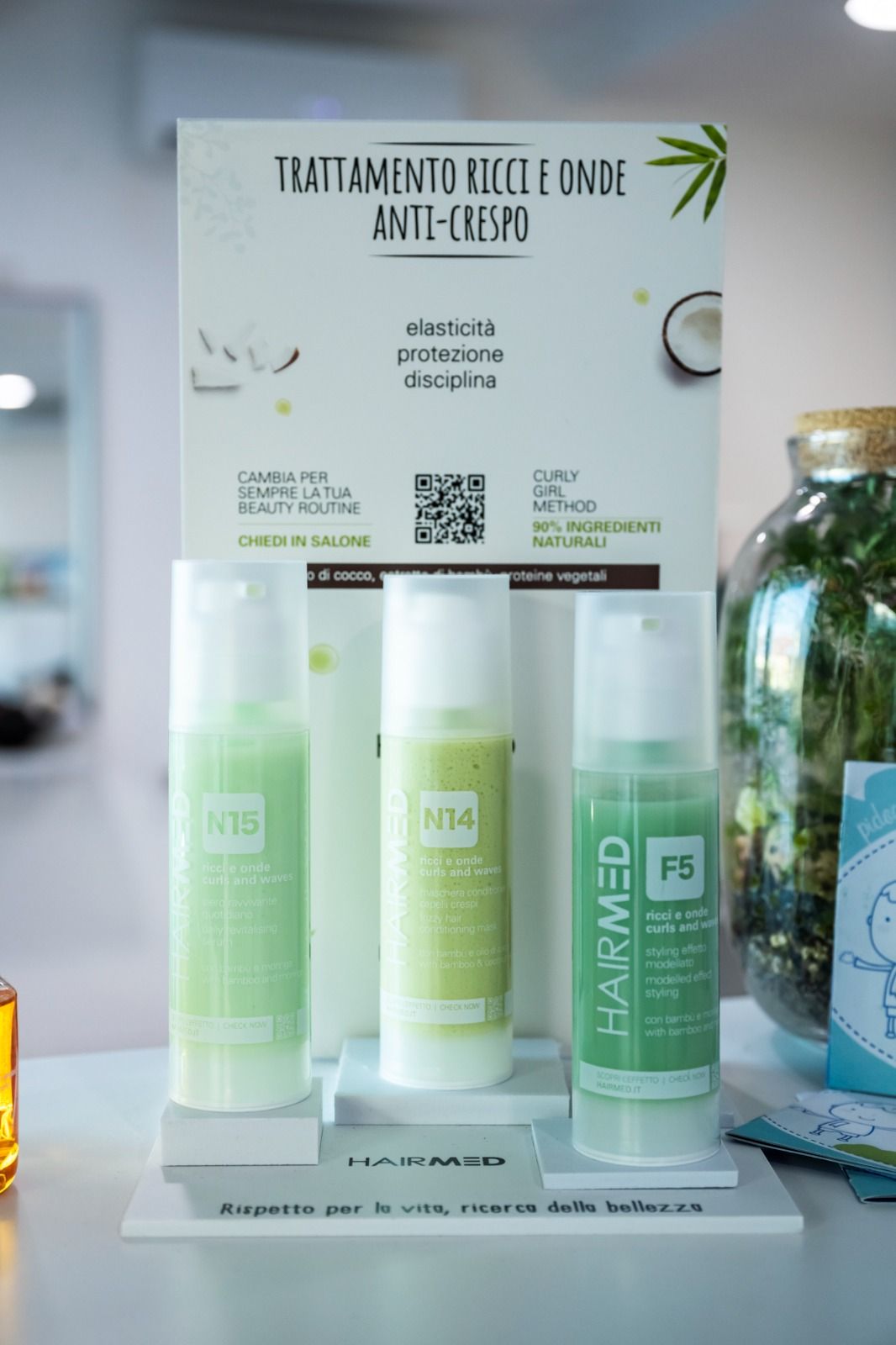 Esposizione di tre prodotti per capelli con etichetta verde e cartello, possibilmente in un salone di bellezza.