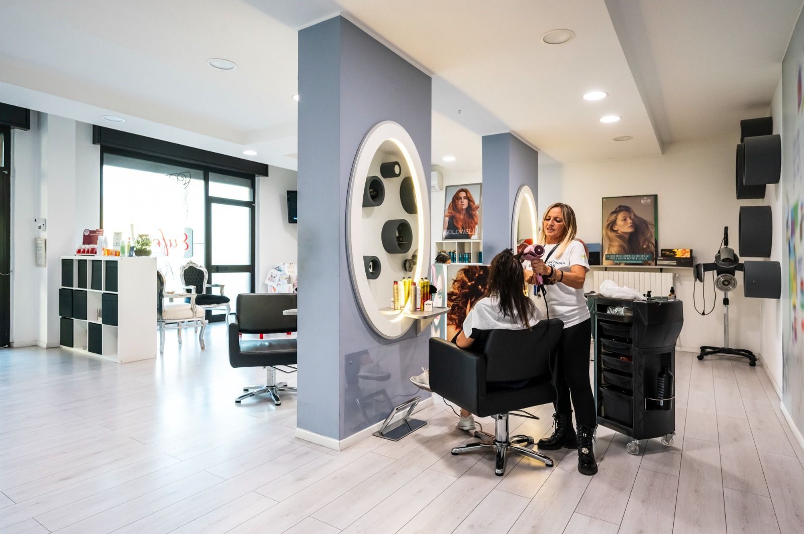 Parrucchiere che acconcia i capelli di una cliente in un salone molto illuminato.