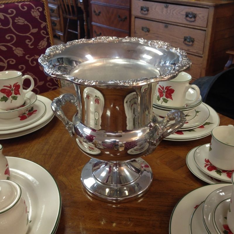 A silver trophy sits on a table surrounded by plates and cups
