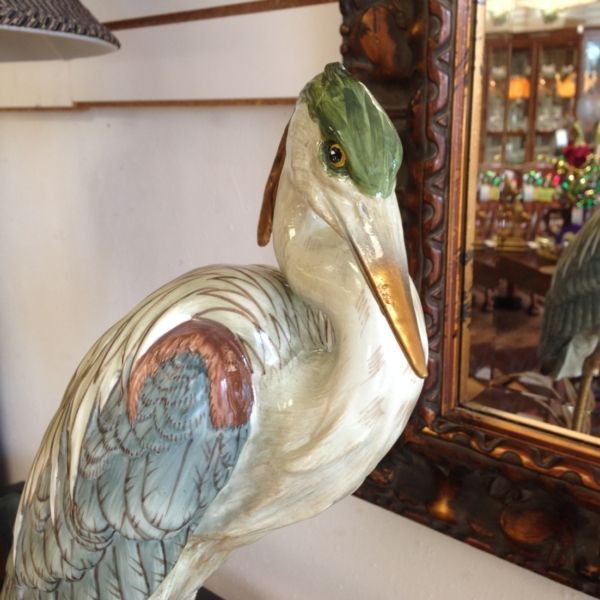 A statue of a bird with a long beak is sitting in front of a mirror