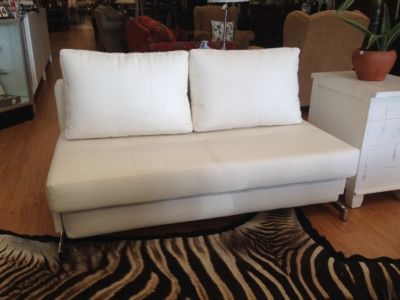 A white couch is sitting on top of a zebra print rug.