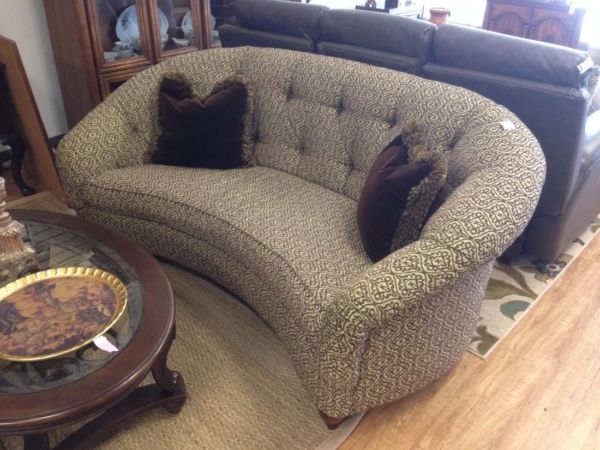A curved couch in a living room next to a coffee table