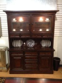 A large wooden cabinet with plates and cups on it.