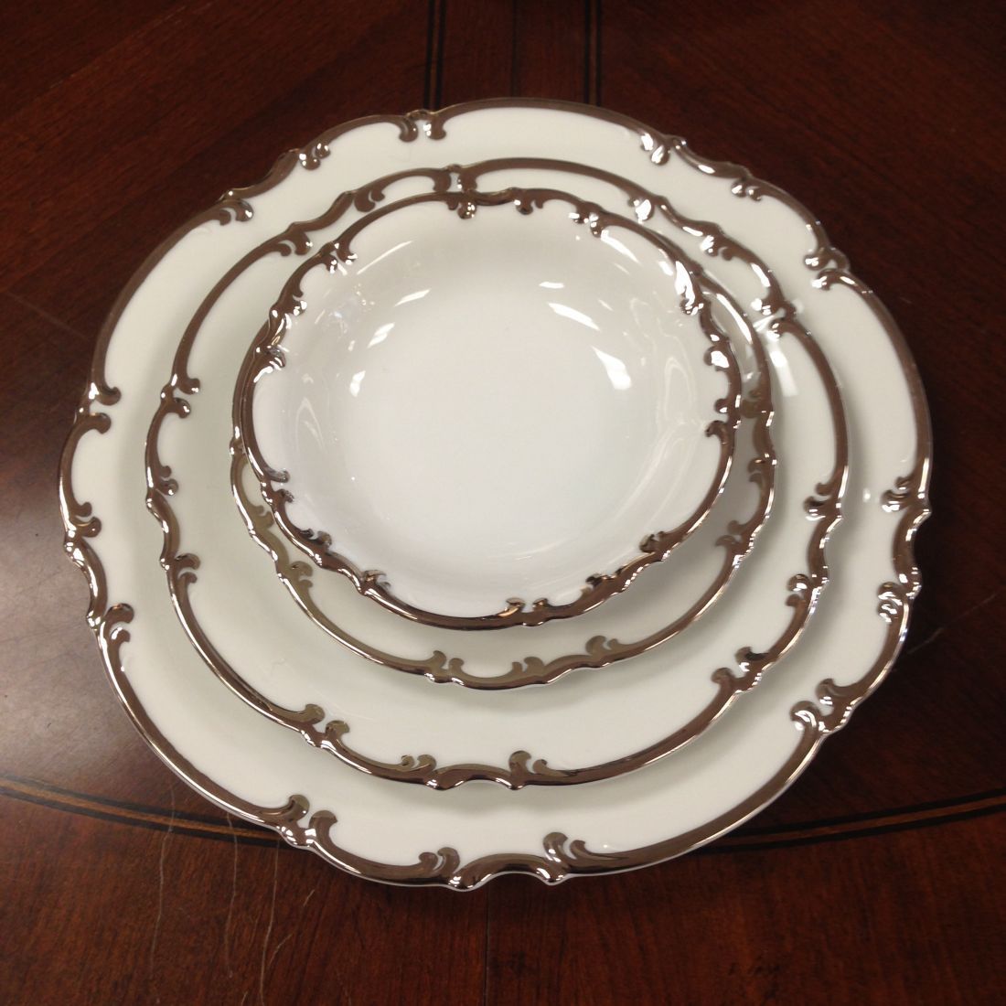 Three white plates with silver rims are stacked on top of each other