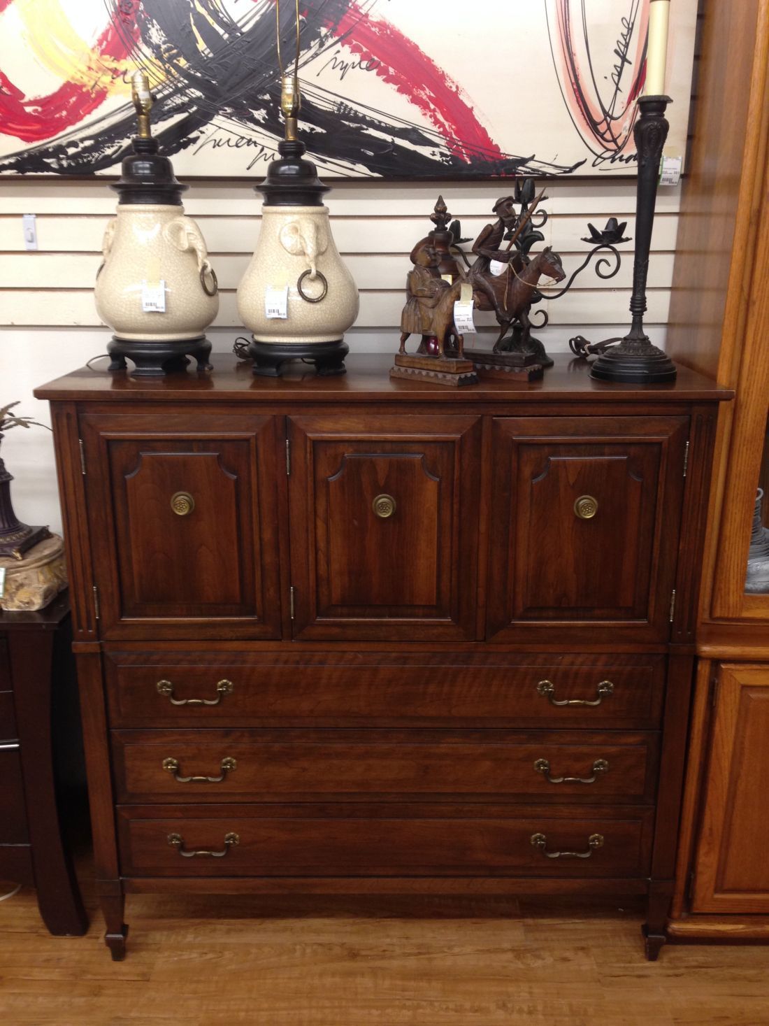 A wooden dresser with three drawers and two vases on top of it