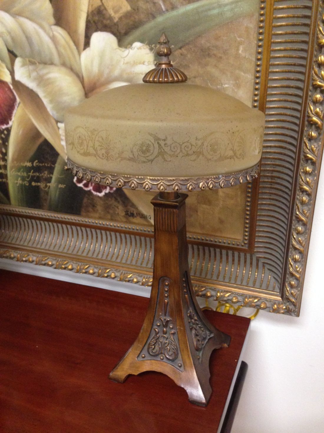 A lamp is sitting on a table in front of a painting