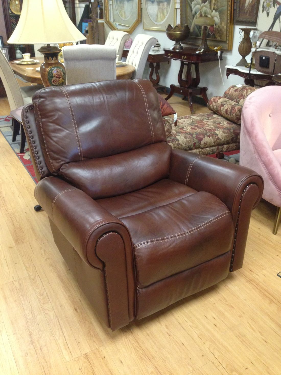 A brown leather recliner is sitting on a wooden floor in a room.