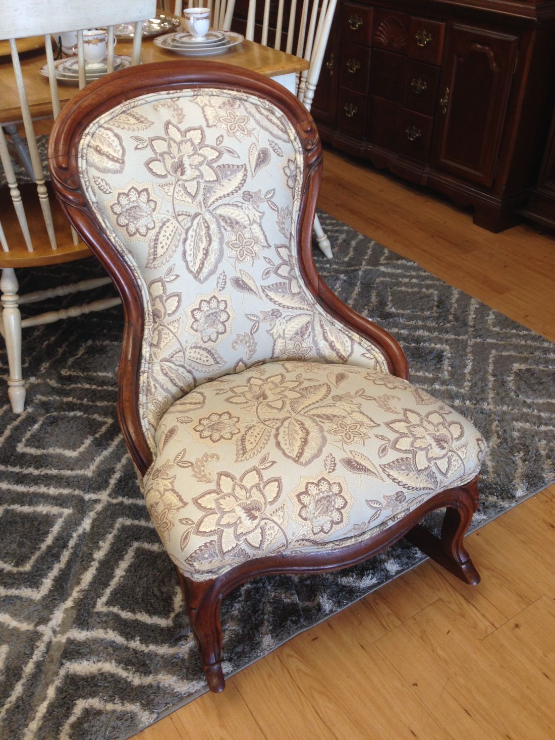 A chair with a floral pattern is sitting on a rug