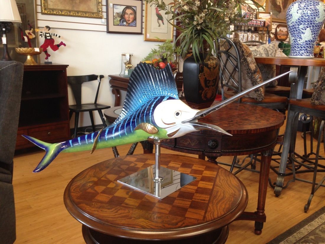A statue of a sailfish is sitting on a wooden table