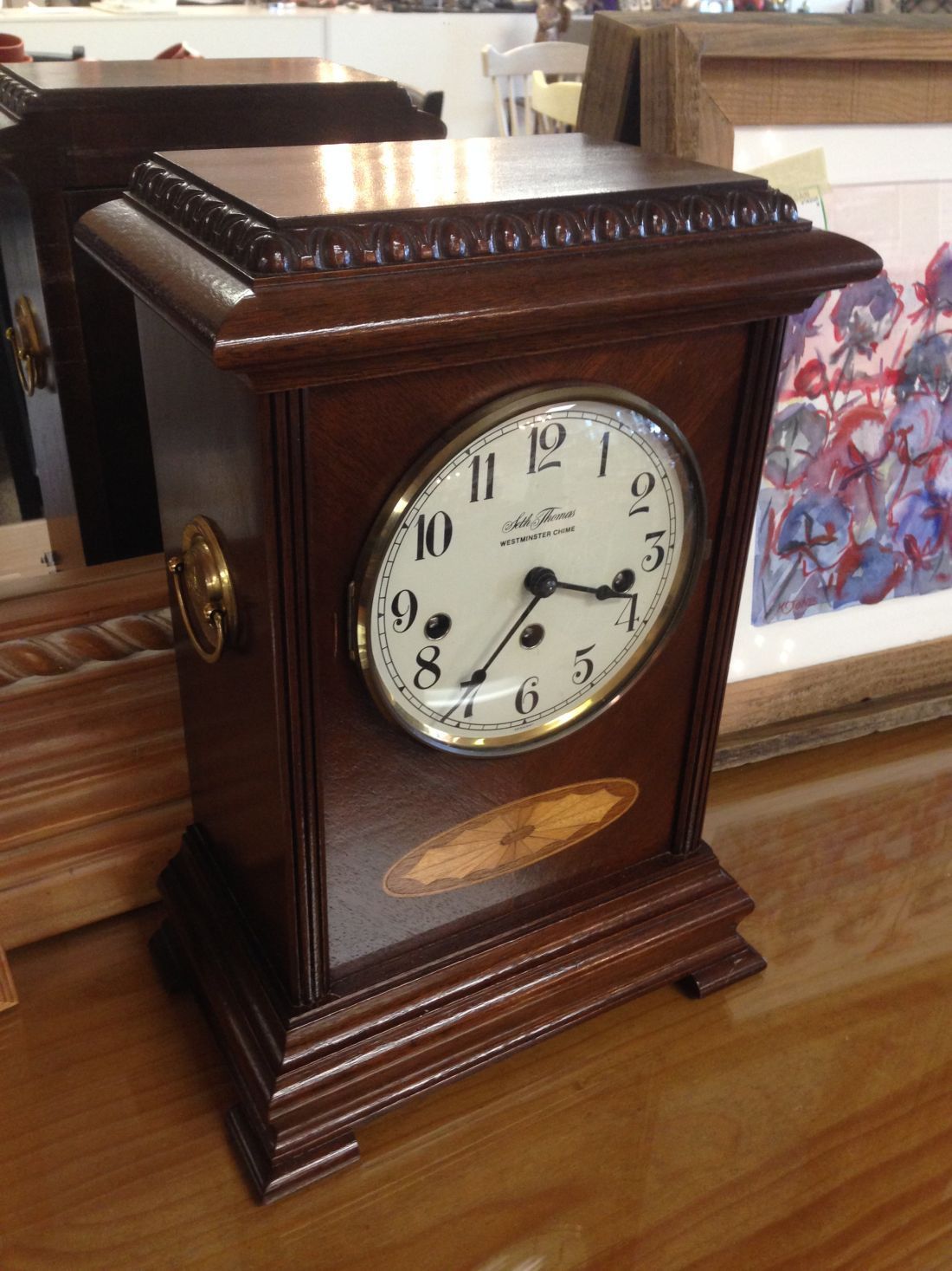 A wooden clock is sitting on a wooden table.