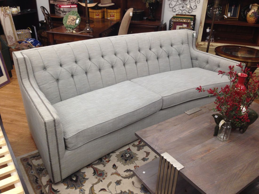A grey couch is sitting on a rug next to a coffee table.