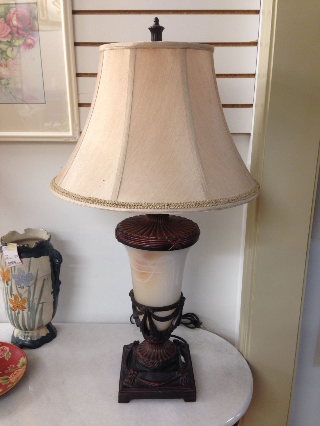 A lamp with a white shade is sitting on a white table.