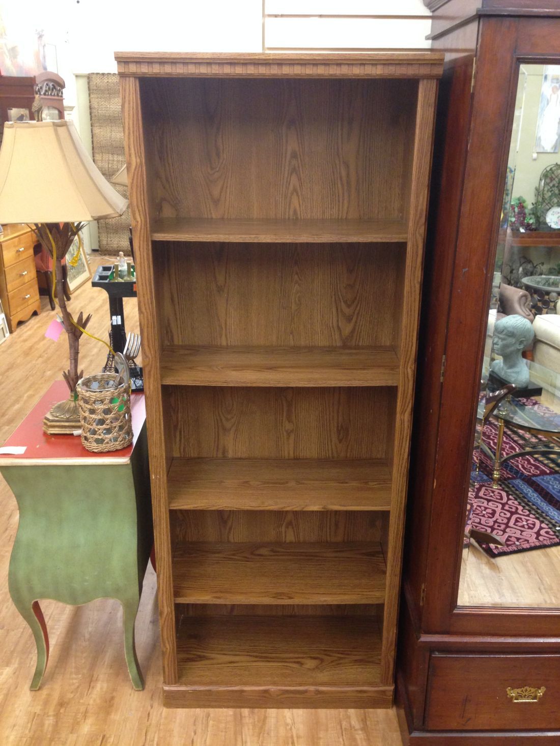An empty wooden bookshelf is sitting on a wooden floor in a room.