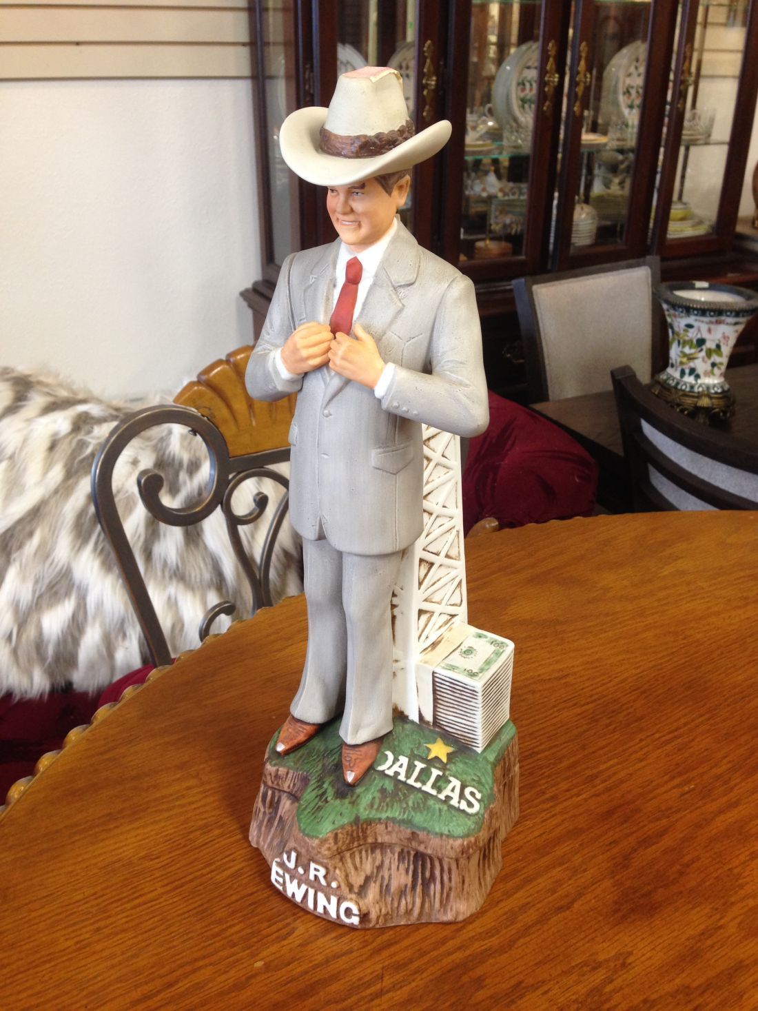A statue of a man in a suit and cowboy hat is sitting on a wooden table.