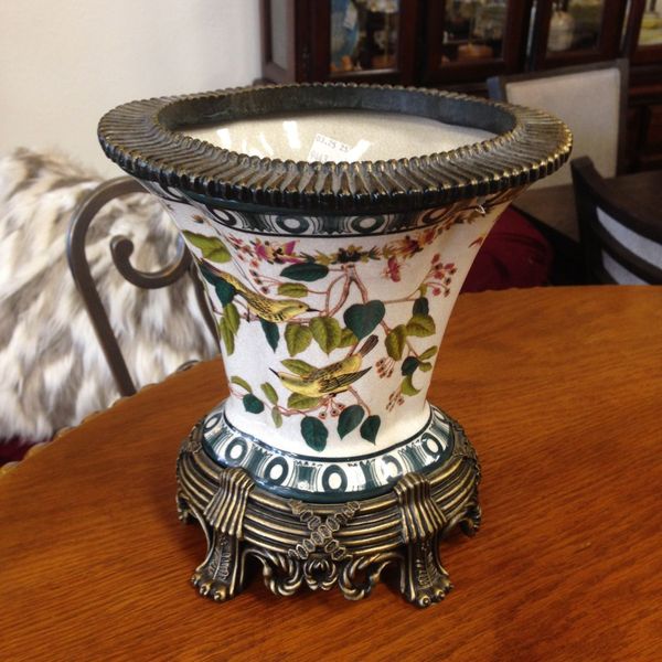 A vase with a floral design sits on a wooden table