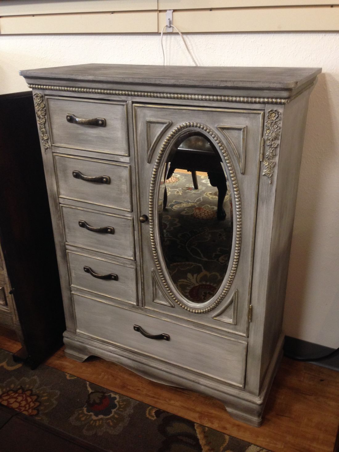 A gray dresser with drawers and a mirror is sitting on a wooden table.