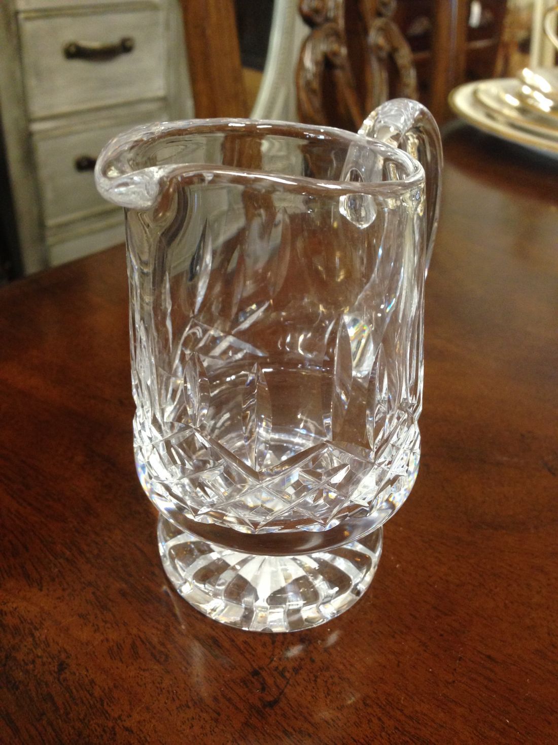 A clear glass pitcher is sitting on a wooden table