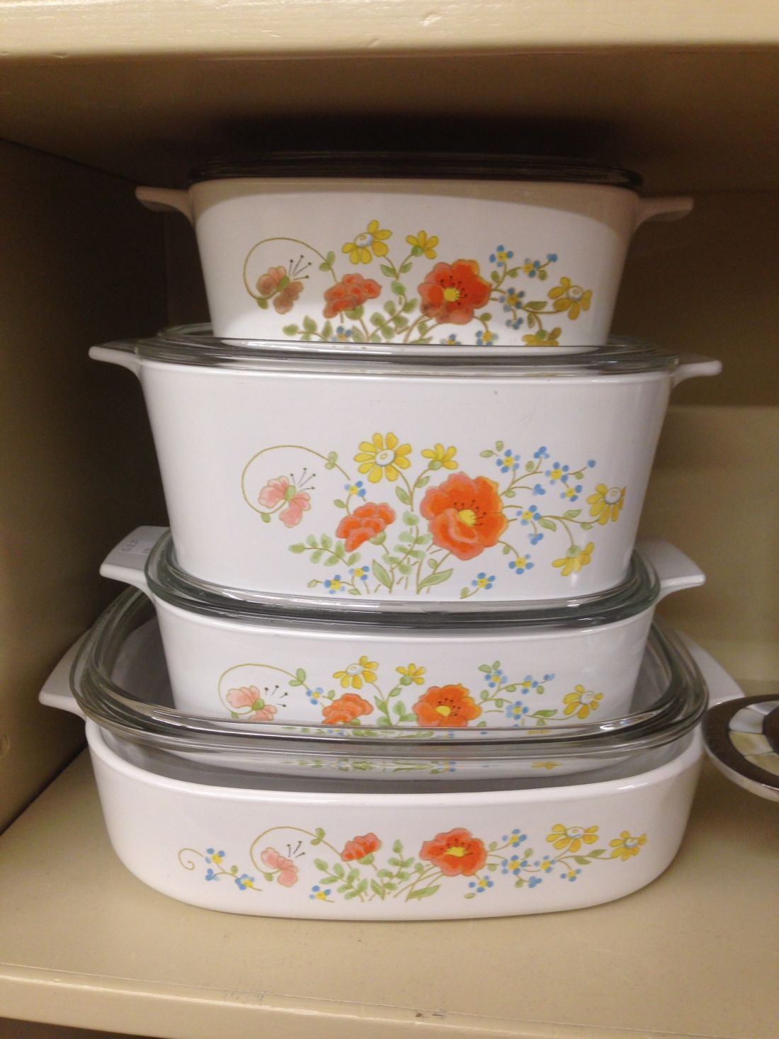 Four casserole dishes are stacked on top of each other on a shelf.
