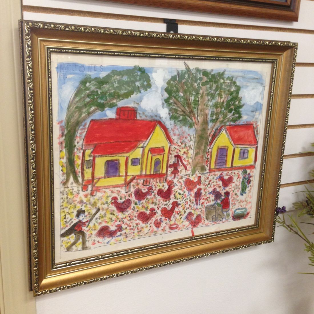 A framed painting of a house with a red roof