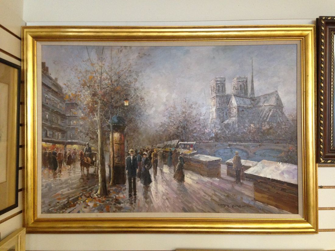 A painting of a city street with a cathedral in the background is hanging on a wall.