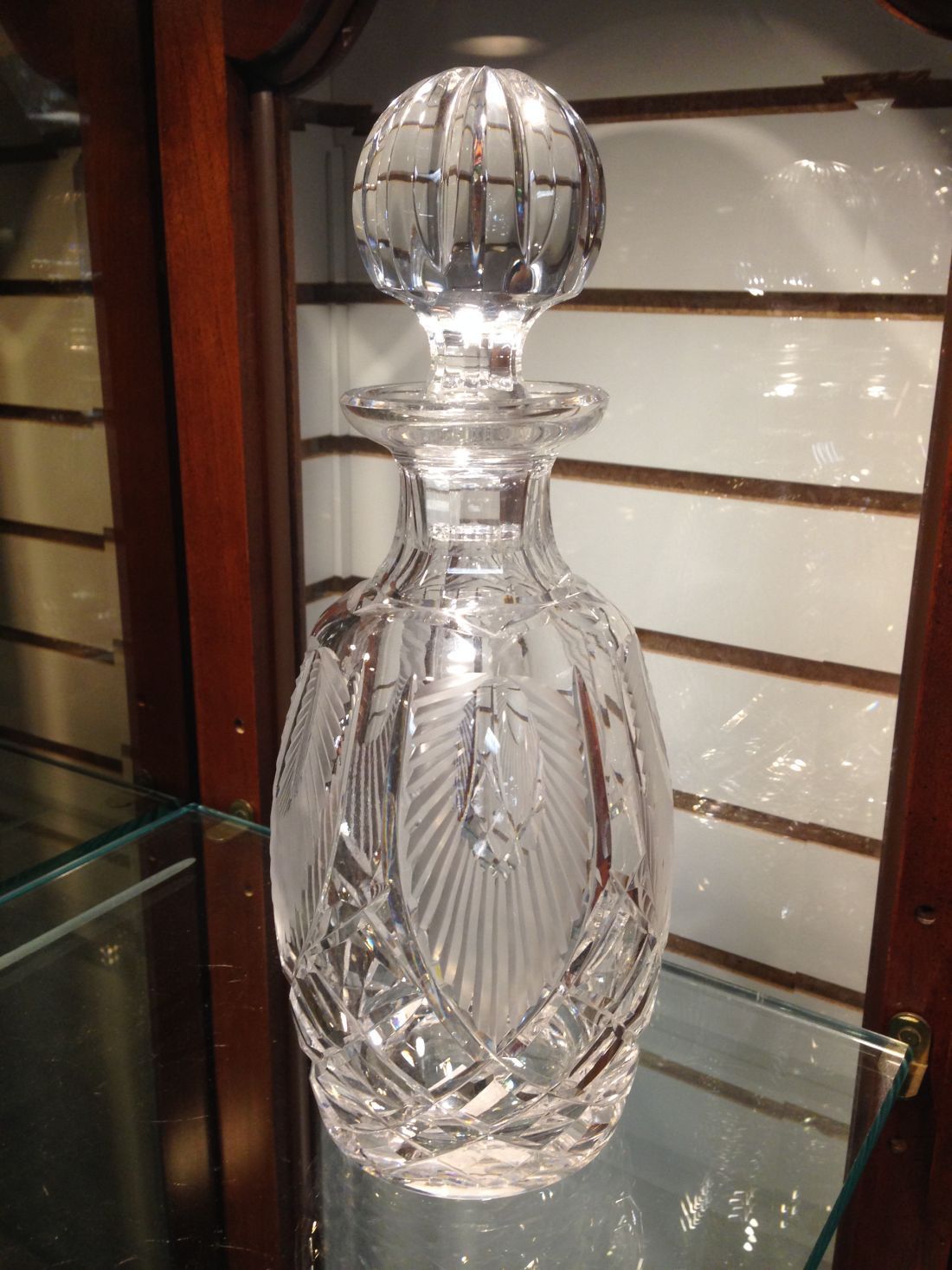 A clear glass bottle is sitting on a glass shelf