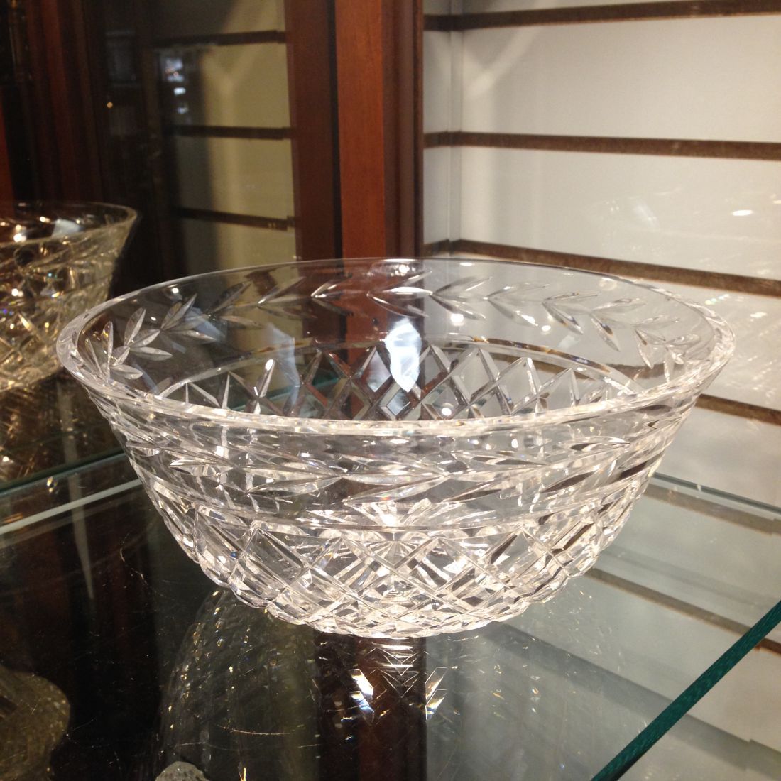 A clear glass bowl sits on a glass shelf