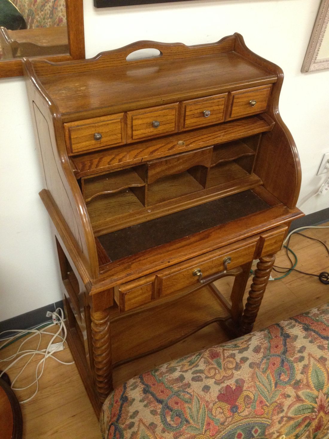 A wooden desk with drawers is sitting next to a bed.