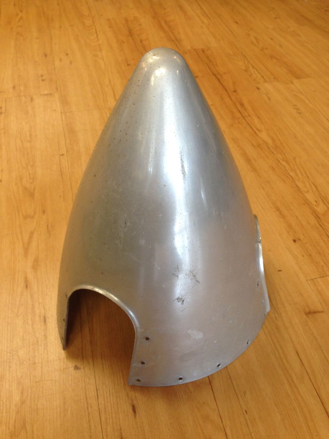 A silver cone is sitting on a wooden floor.