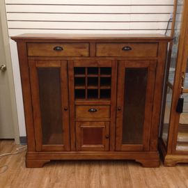 A wooden cabinet with glass doors and drawers