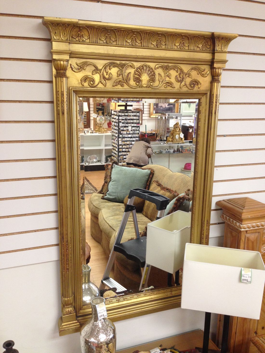 A large gold mirror is hanging on a wall in a room