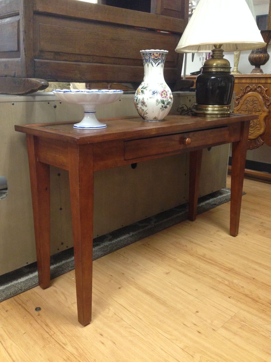A wooden table with a vase and a lamp on it.