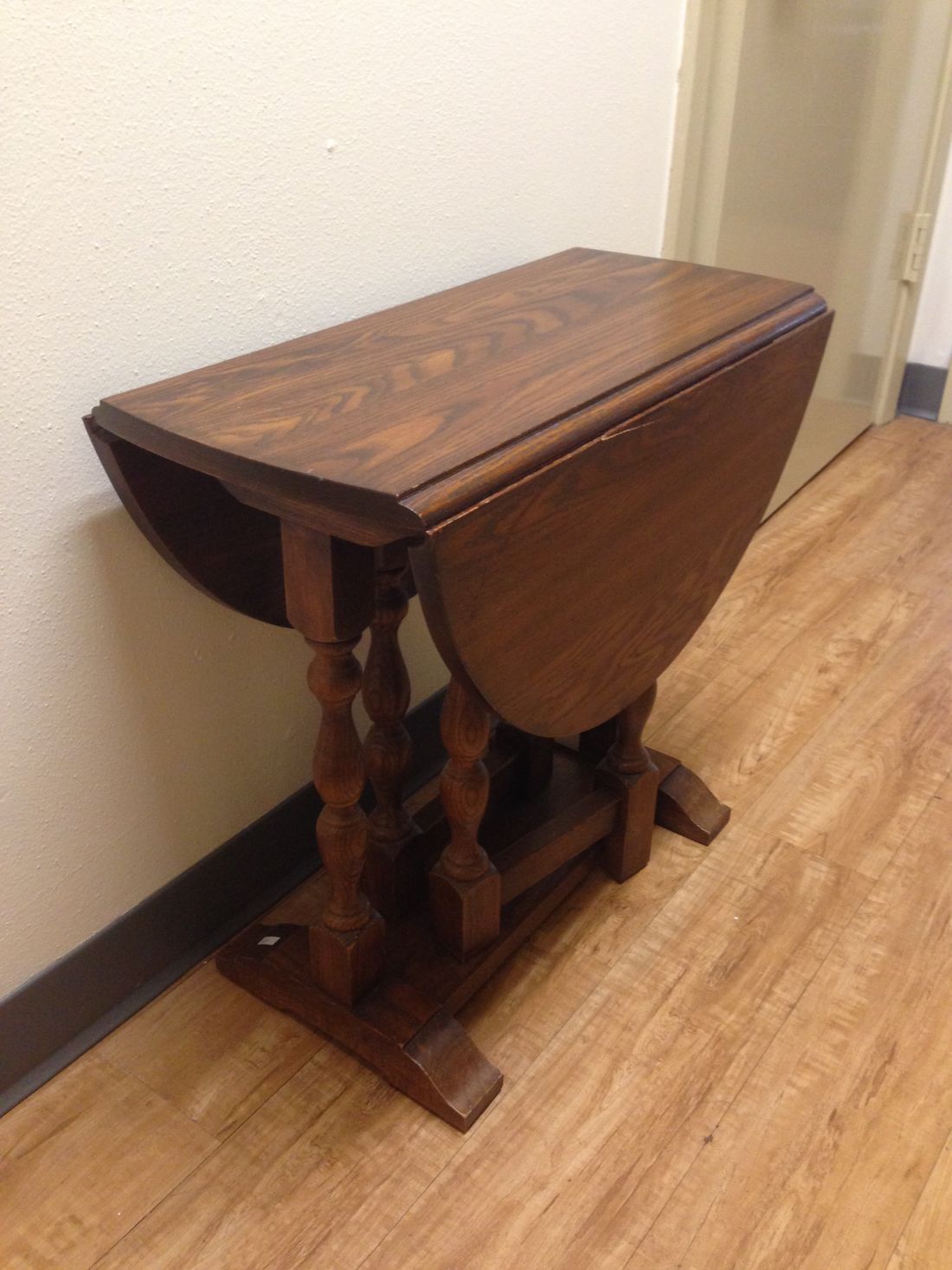 A small wooden table is sitting on a wooden floor in a hallway.
