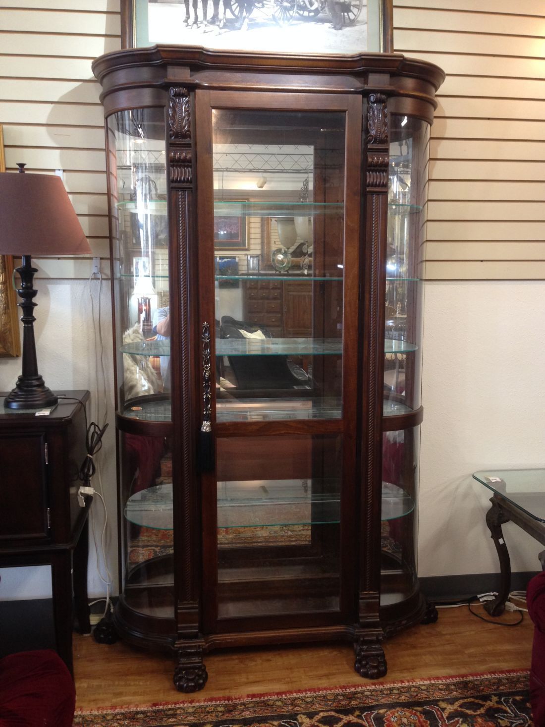 A curio cabinet is sitting in a living room next to a lamp.