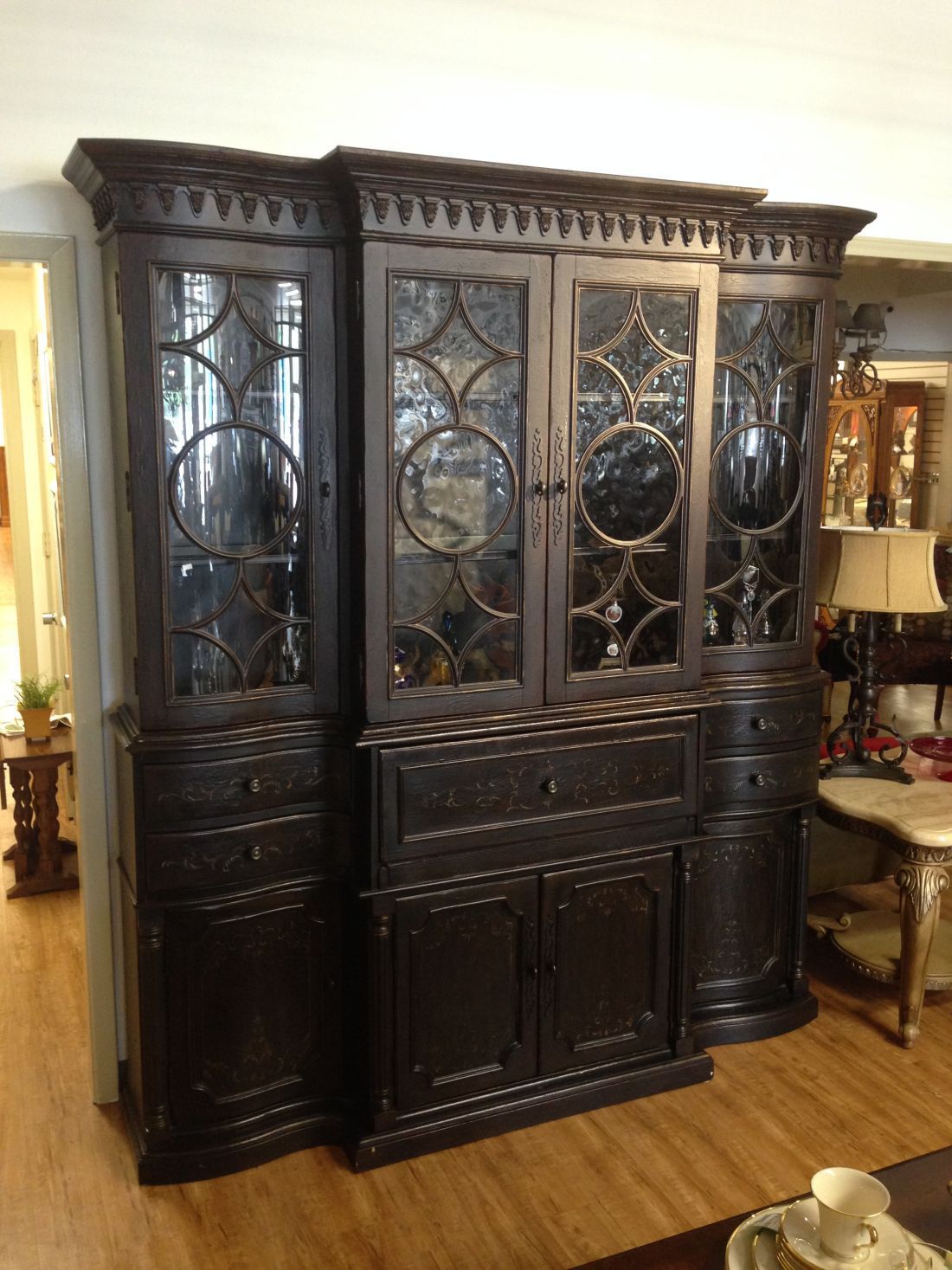 A large wooden cabinet with glass doors and drawers in a living room.
