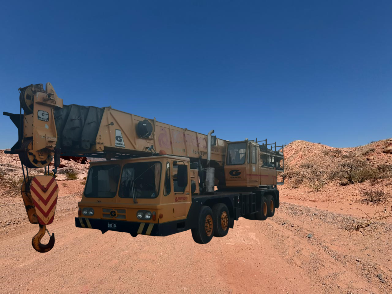 Camión grúa amarillo en paisaje desértico con cielo azul.