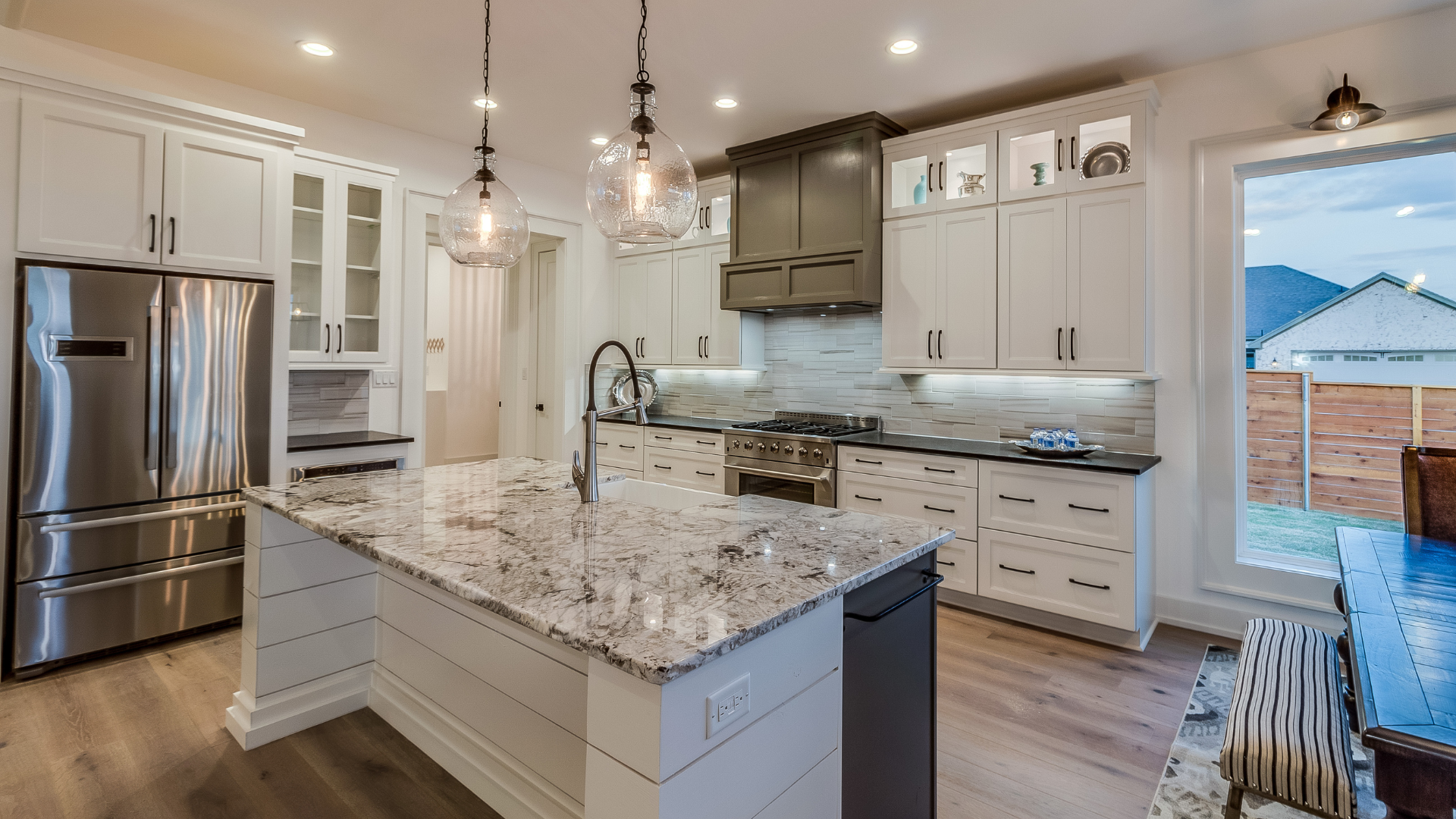 A kitchen with white cabinets , granite counter tops , stainless steel appliances and a large island.