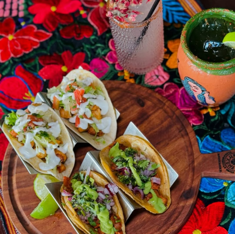 A wooden cutting board topped with tacos and a drink
