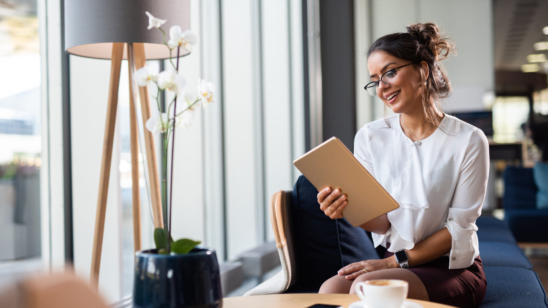 A woman is sitting at a table using a tablet computer.