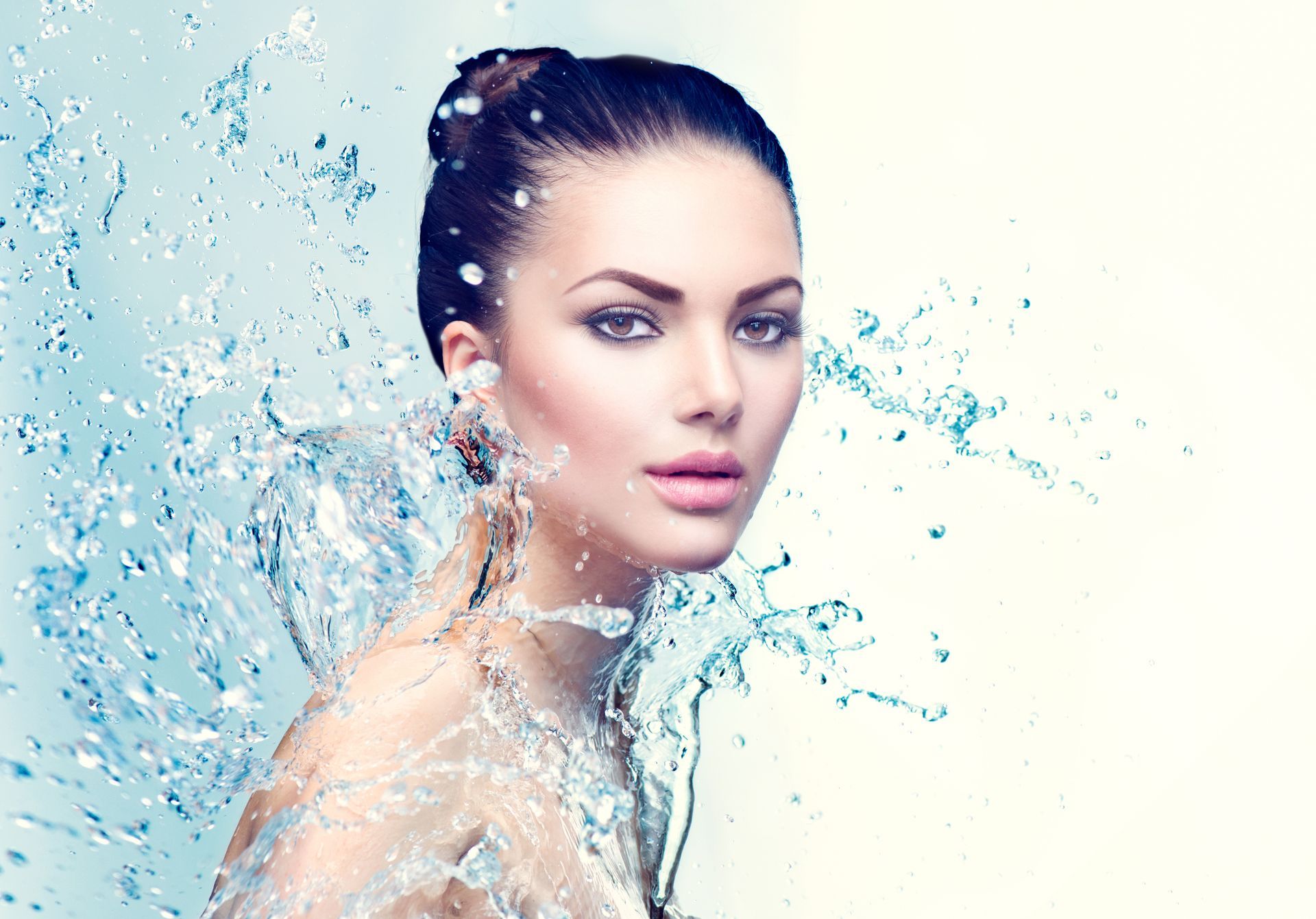 Eine Frau spritzt sich Wasser ins Gesicht.
