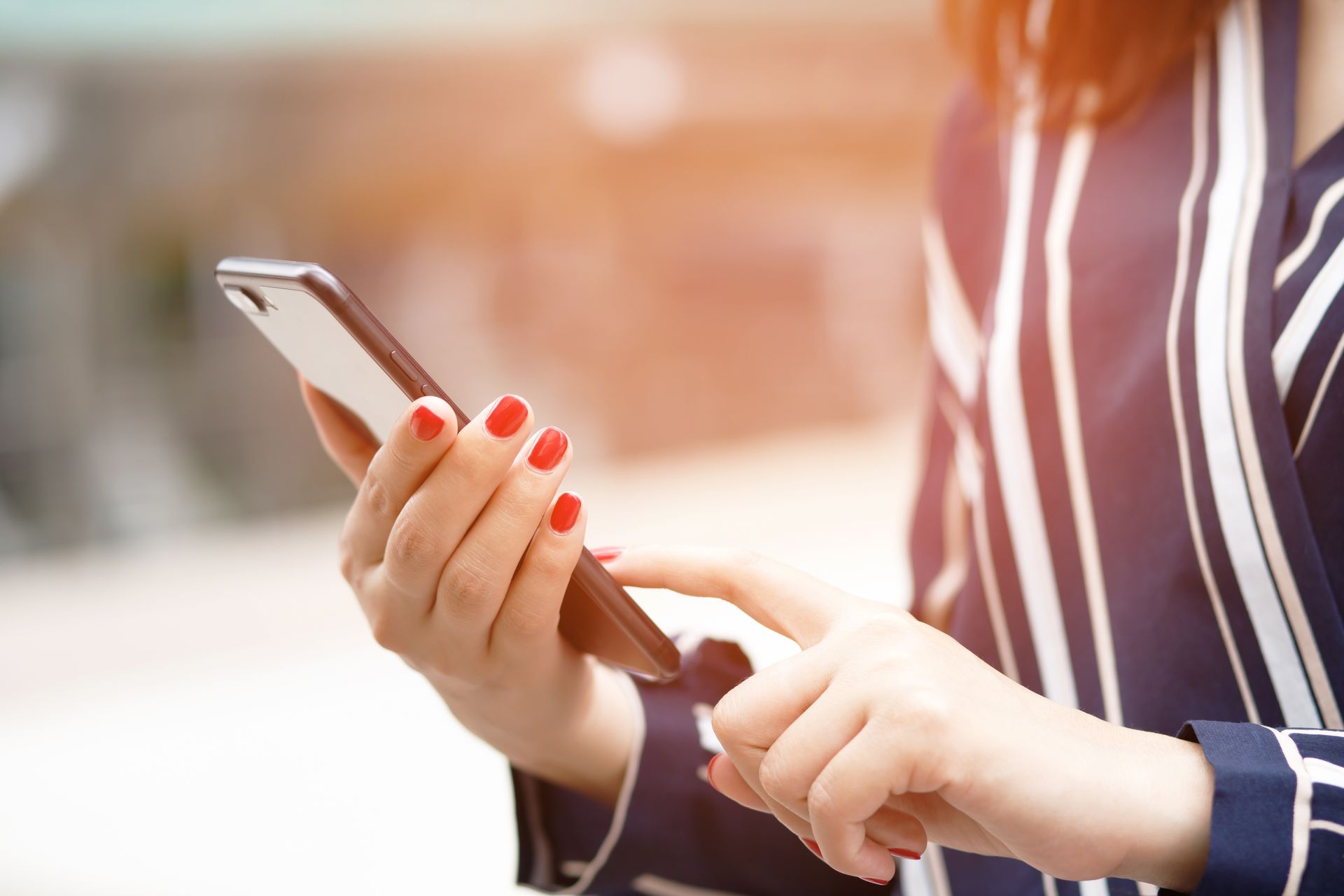 Eine Frau mit roten Nägeln benutzt ein Mobiltelefon.