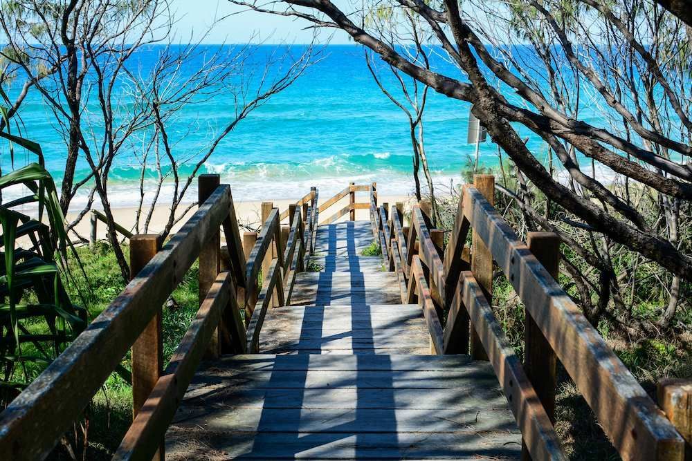 A Wooden Walkway Leading to the Beach With a View of the Ocean — O'Brien Painting Contractors in Mooloolaba, QLD
