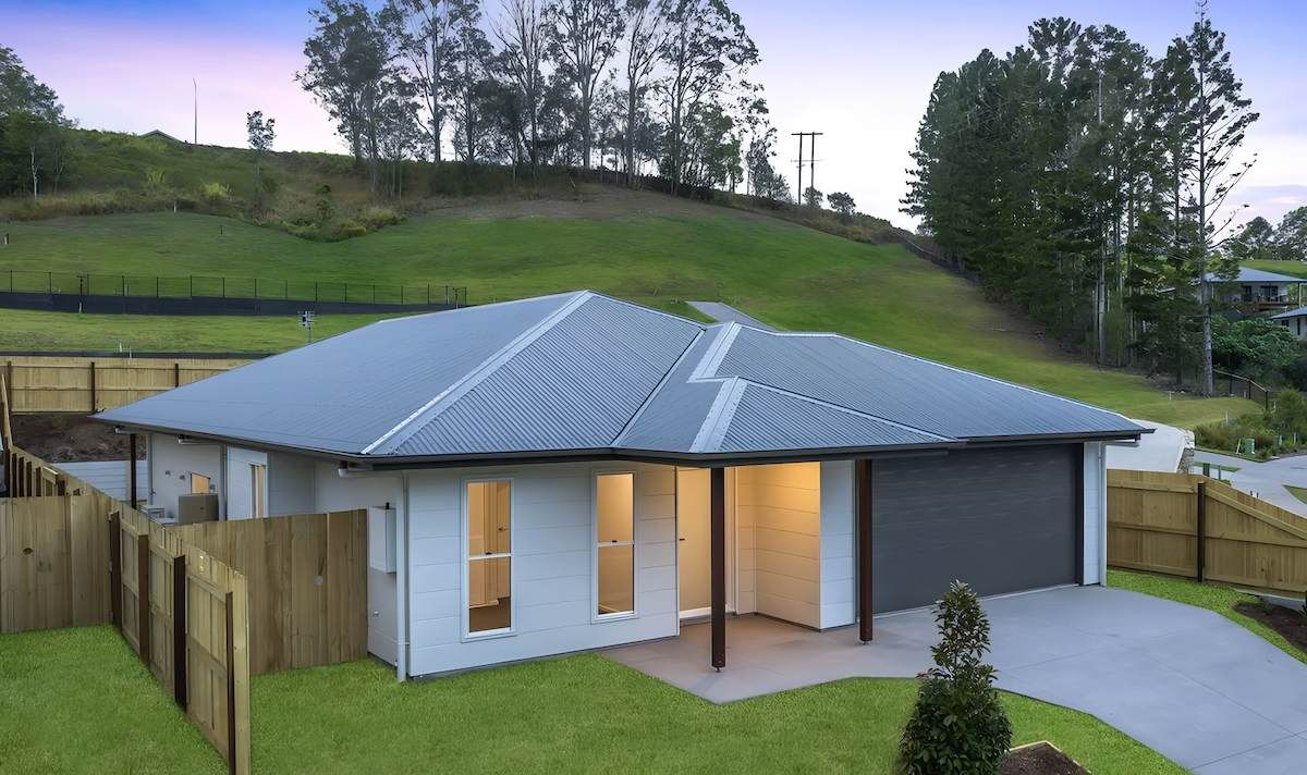 A White House With a Gray Roof is Sitting on Top of a Lush — O'Brien Painting Contractors in Alexandra Headland, QLD